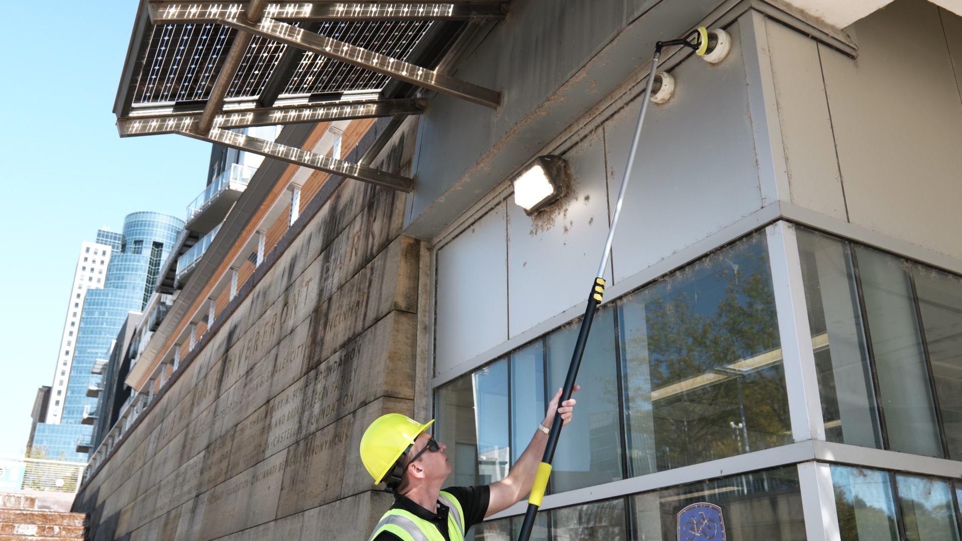 CameraShine technician cleaning a side-mounted dome security camera from the ground